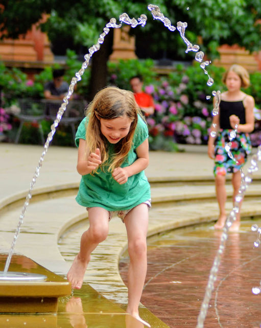 Girl playing in outdoor fountain