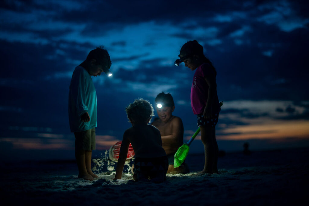 Children with head torches at the beach at night
